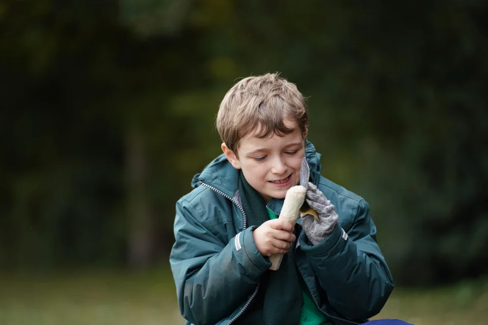 Child concentrating on a hands-on bushcraft task