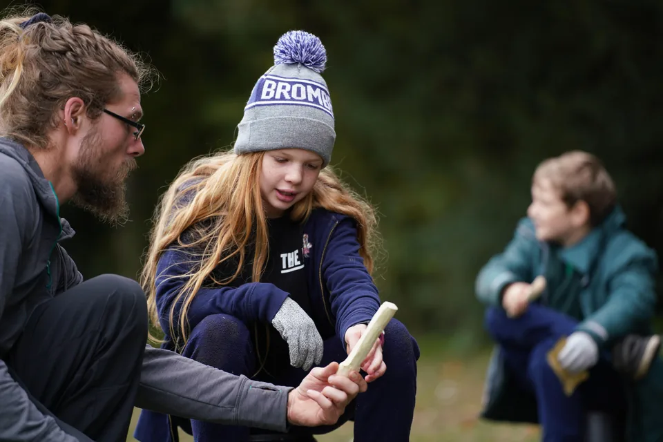 Instructor guiding a child through a bushcraft task