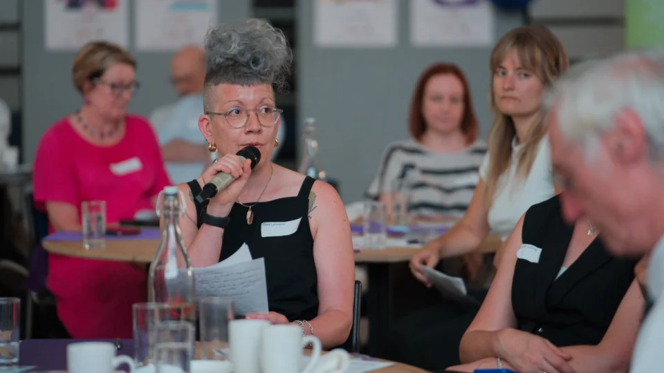 Guest speaking into a microphone from her table during an anniversary discussion