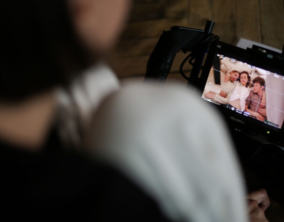 A film crew member reviews footage on a monitor, capturing a behind-the-scenes look at the creative process