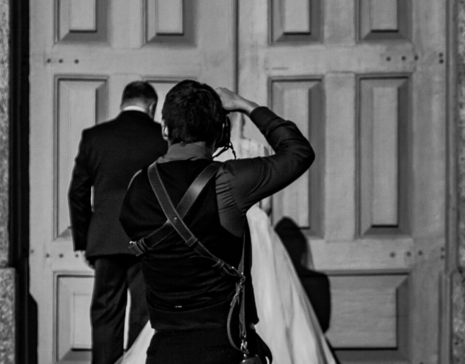 A photographer captures a wedding couple entering a church in black and white