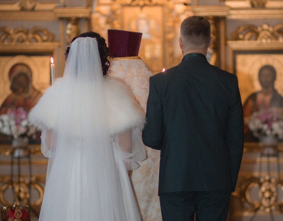 Bride and groom stand before a golden church altar during their wedding ceremony