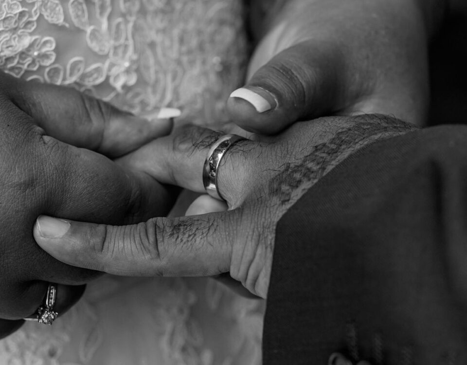 Black and white close-up of a couple exchanging rings at their wedding ceremony