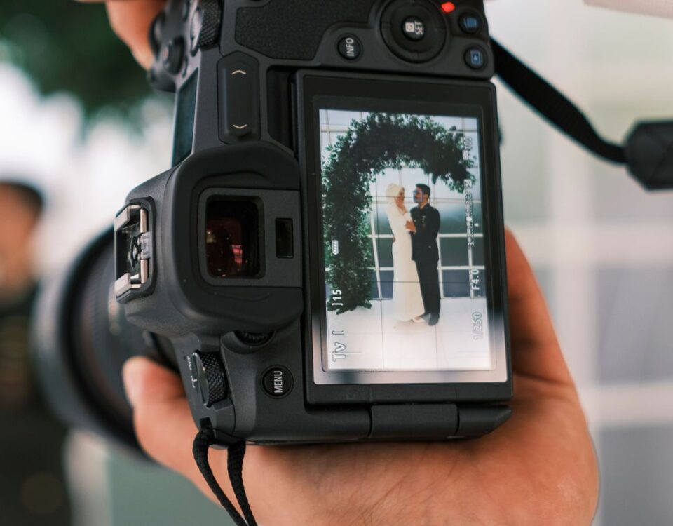 A wedding photographer captures a couple's joyful moment through the camera's viewfinder