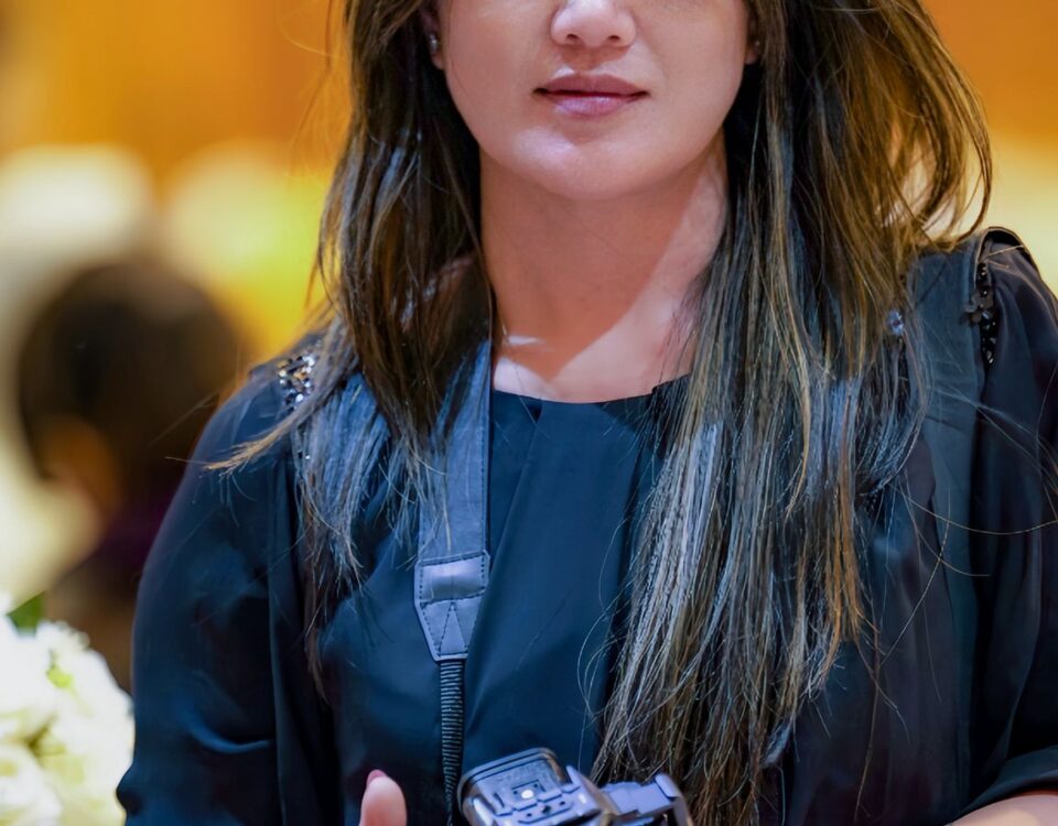 Portrait of a female photographer holding a camera at an indoor event, conveying professionalism and focus