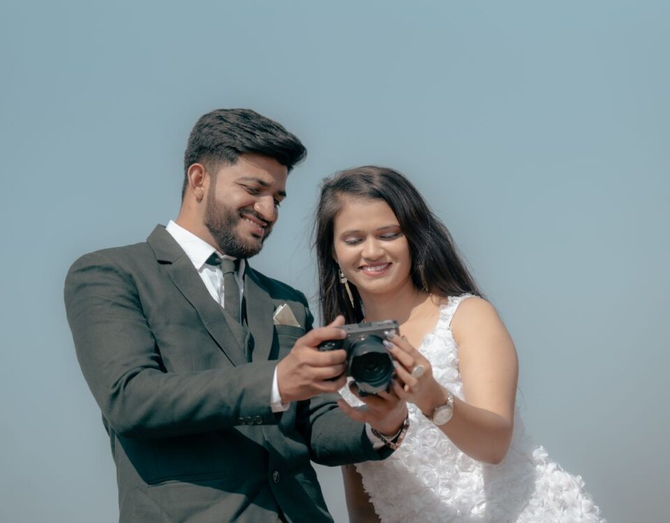 Smiling couple reviewing photos on camera during an outdoor pre-wedding shoot
