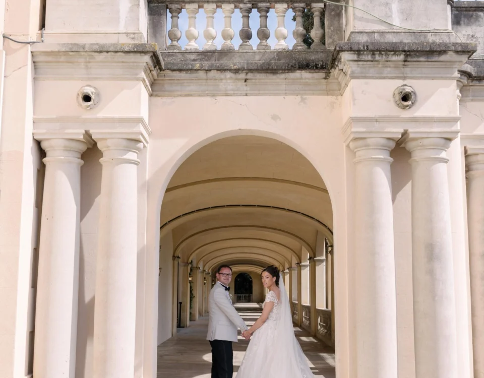 Wedding couple walking beneath a grand stone archway