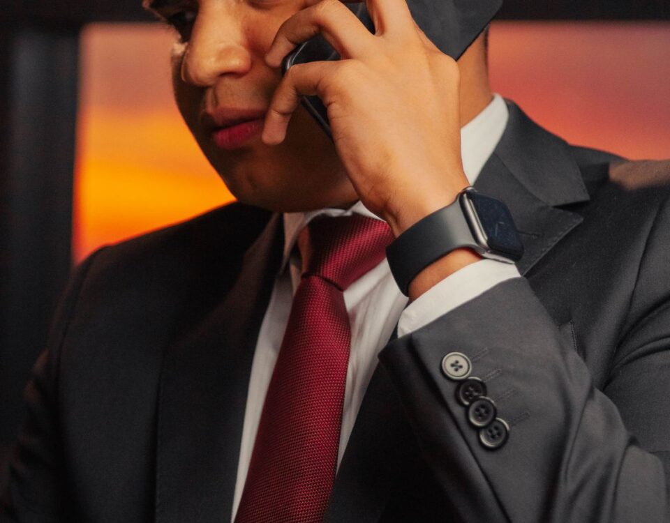 Professional man in a suit making a phone call with a smartphone during sunset indoors