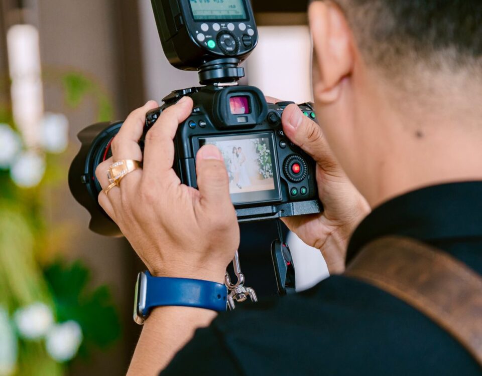 Close-up of a photographer using a camera with flash indoors, focusing on a screen view