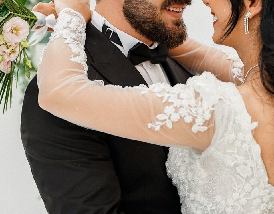 Smiling bride and groom embrace lovingly in elegant wedding attire