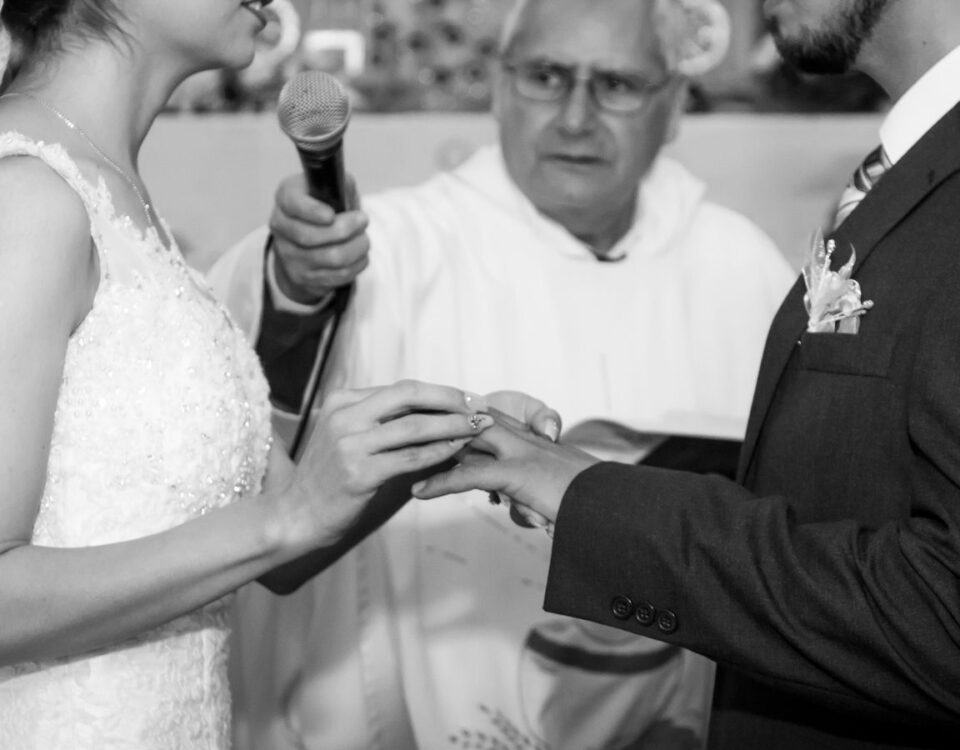 A monochrome image capturing a couple exchanging rings during their wedding ceremony
