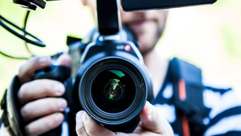 A close-up shot of a cameraman filming, focusing on the camera lens and equipment