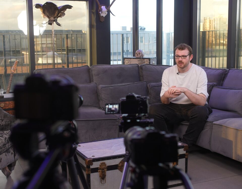 Cameras recording a seated speaker in a lounge-style interview setup