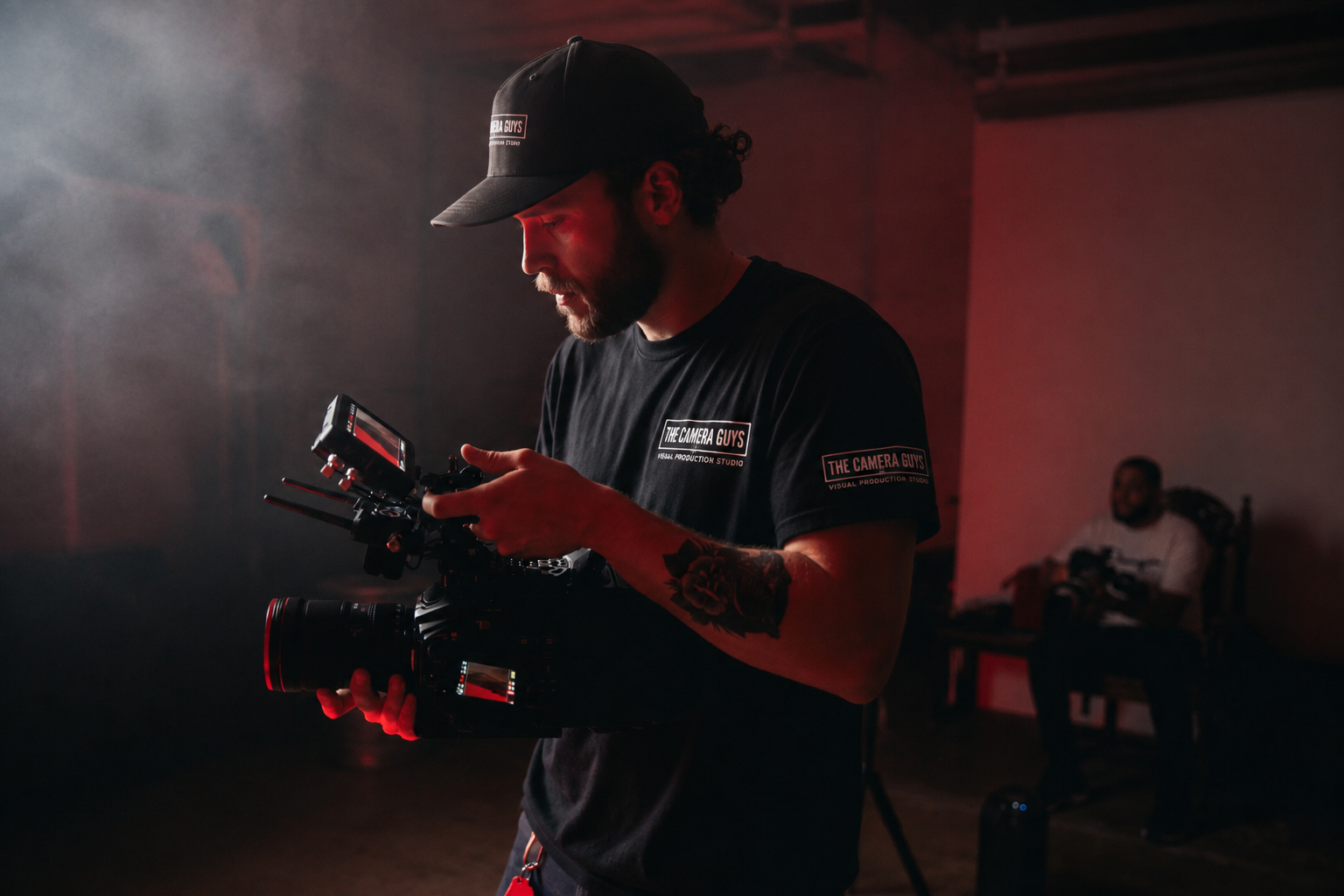 Videographer checking a cinema camera in a dark studio with red lighting