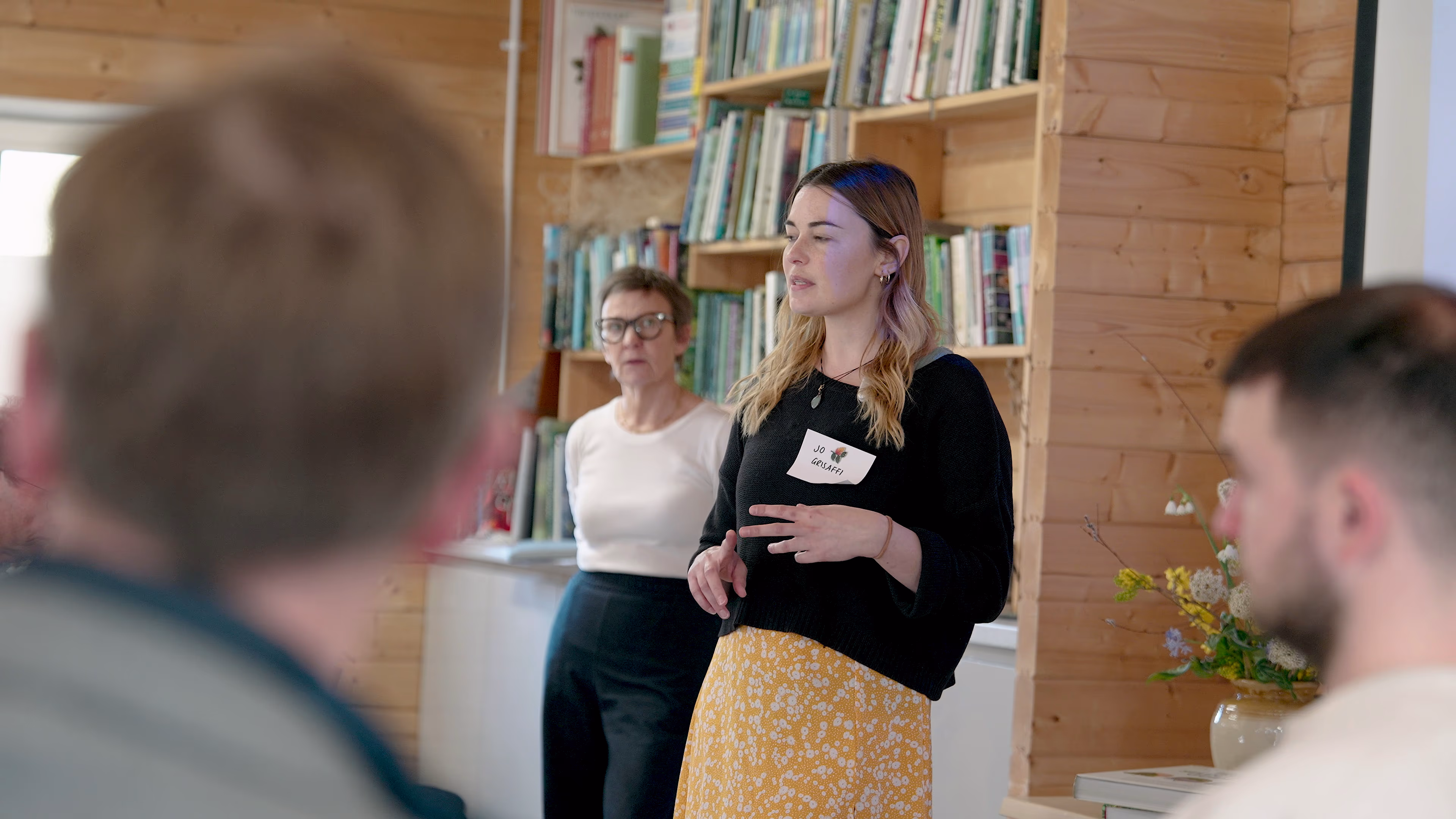 Participant speaking to the workshop group beside bookshelves