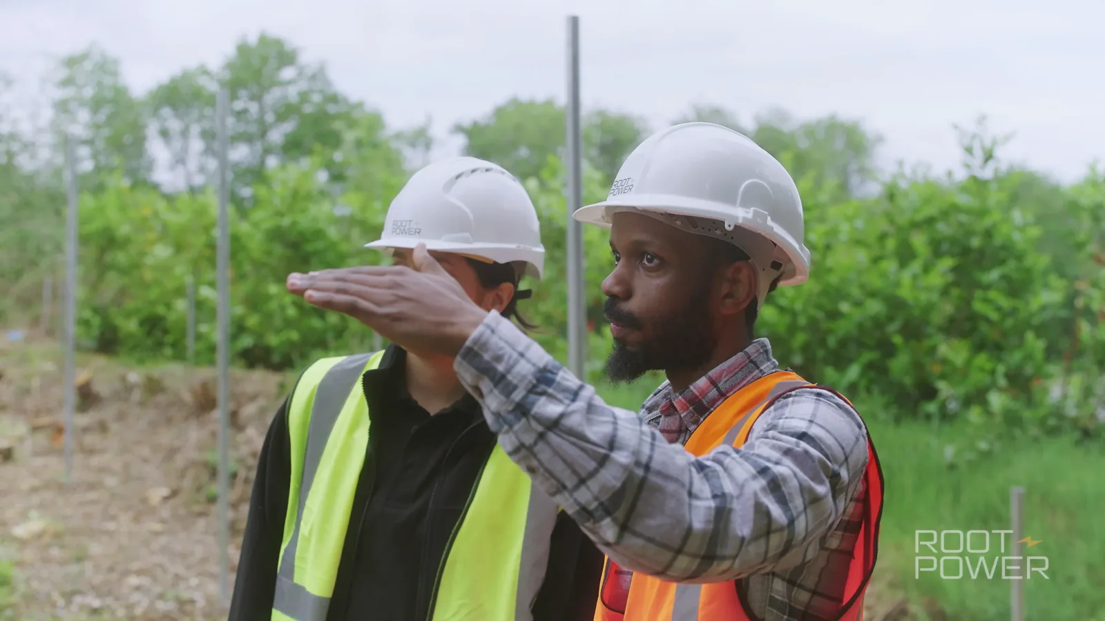 Two Root-Power team members discussing the Coryton site in hard hats and high-visibility clothing