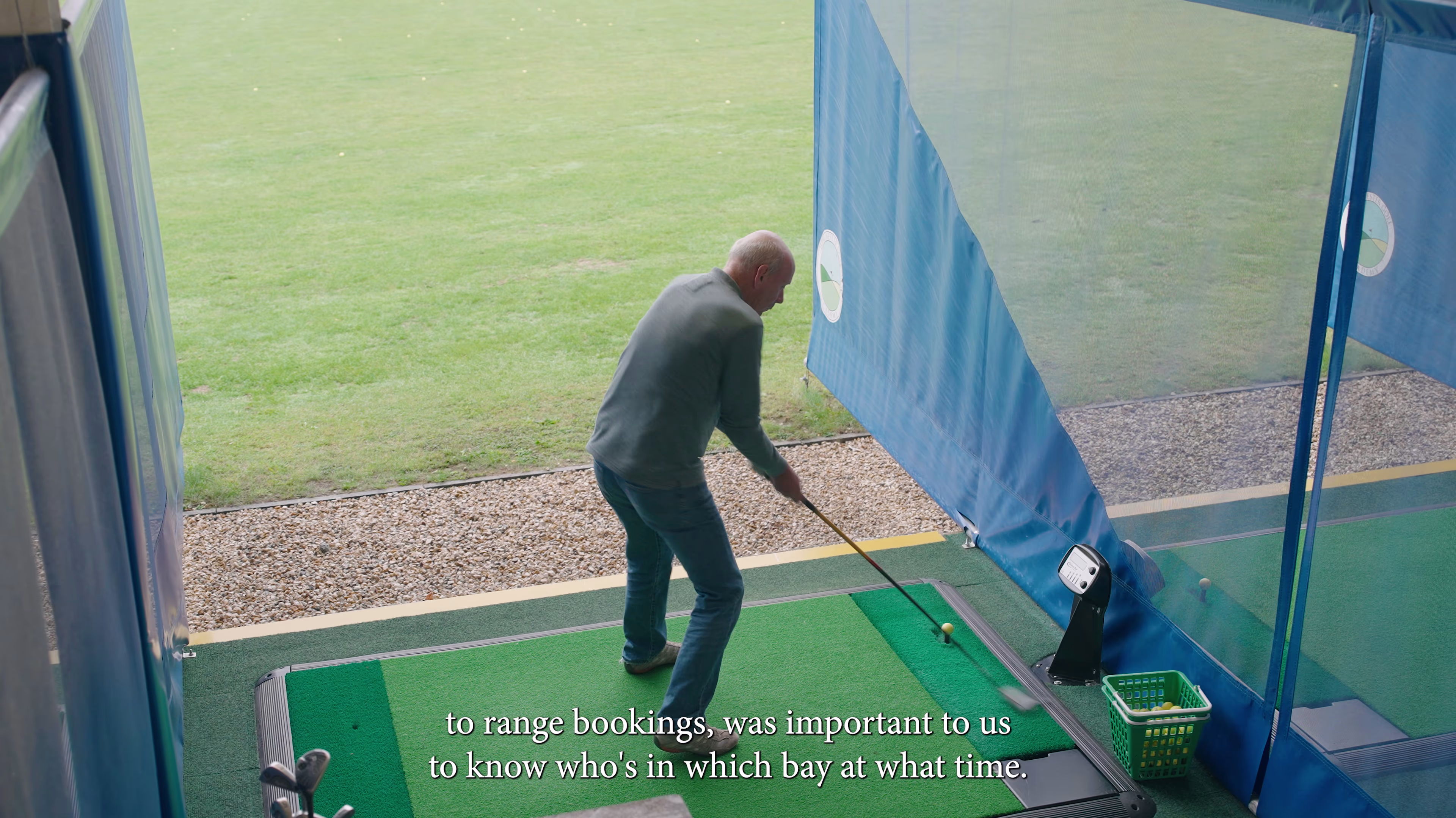 Golfer playing a shot from a covered driving-range bay