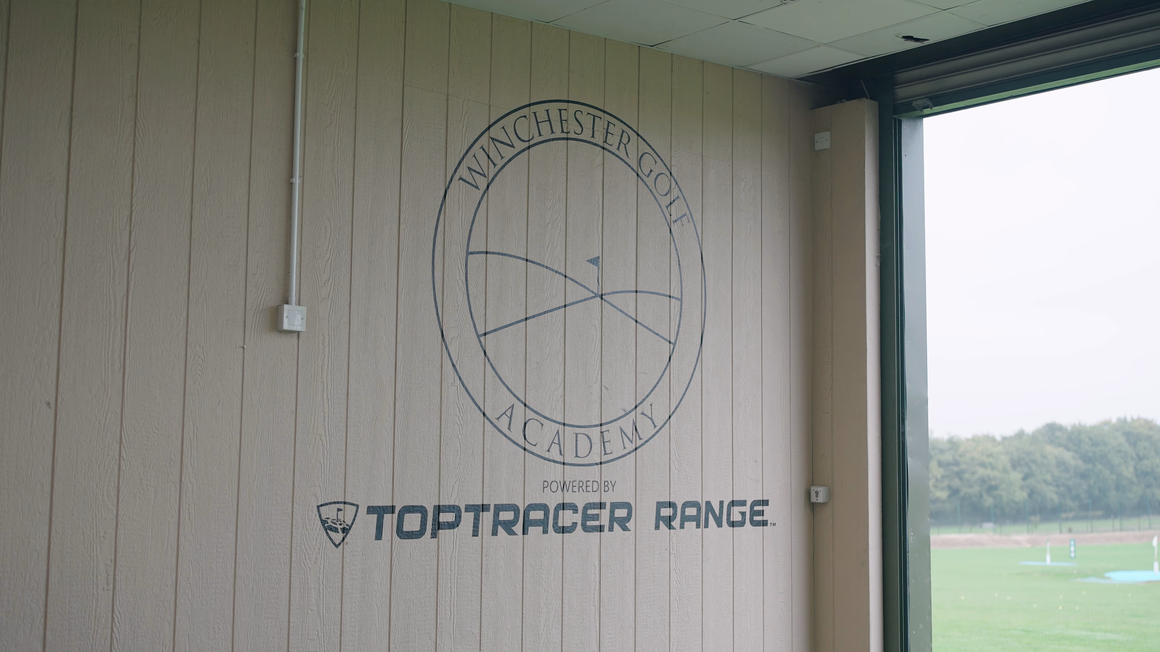 Winchester Golf Academy and Toptracer Range branding beside a window