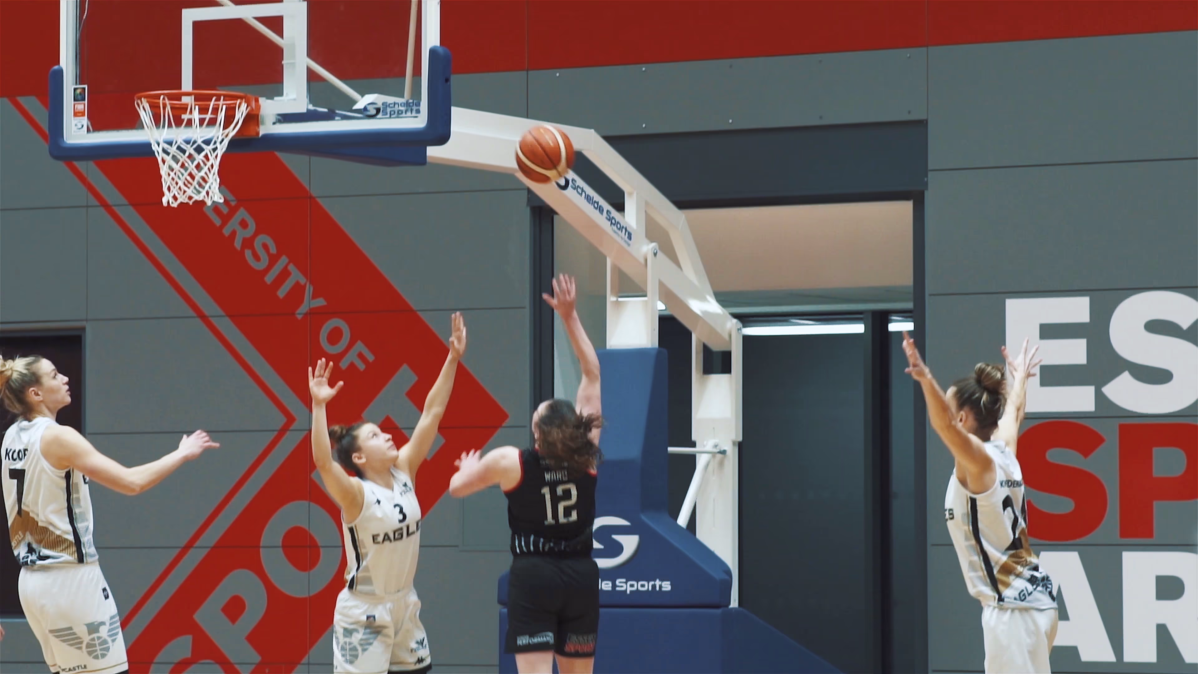 Women's basketball players contesting a shot near the basket