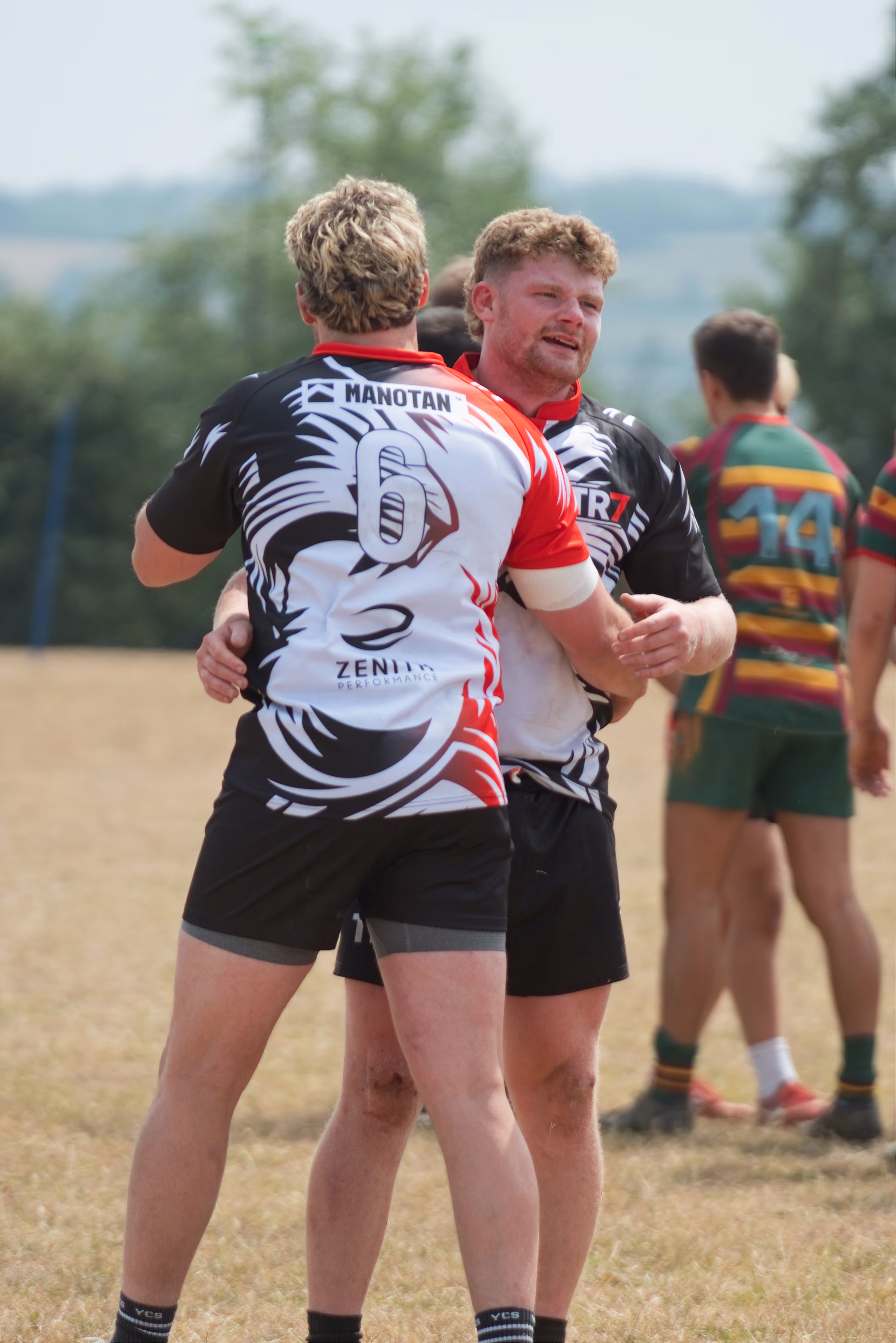 TR7 teammates embracing beside the rugby pitch