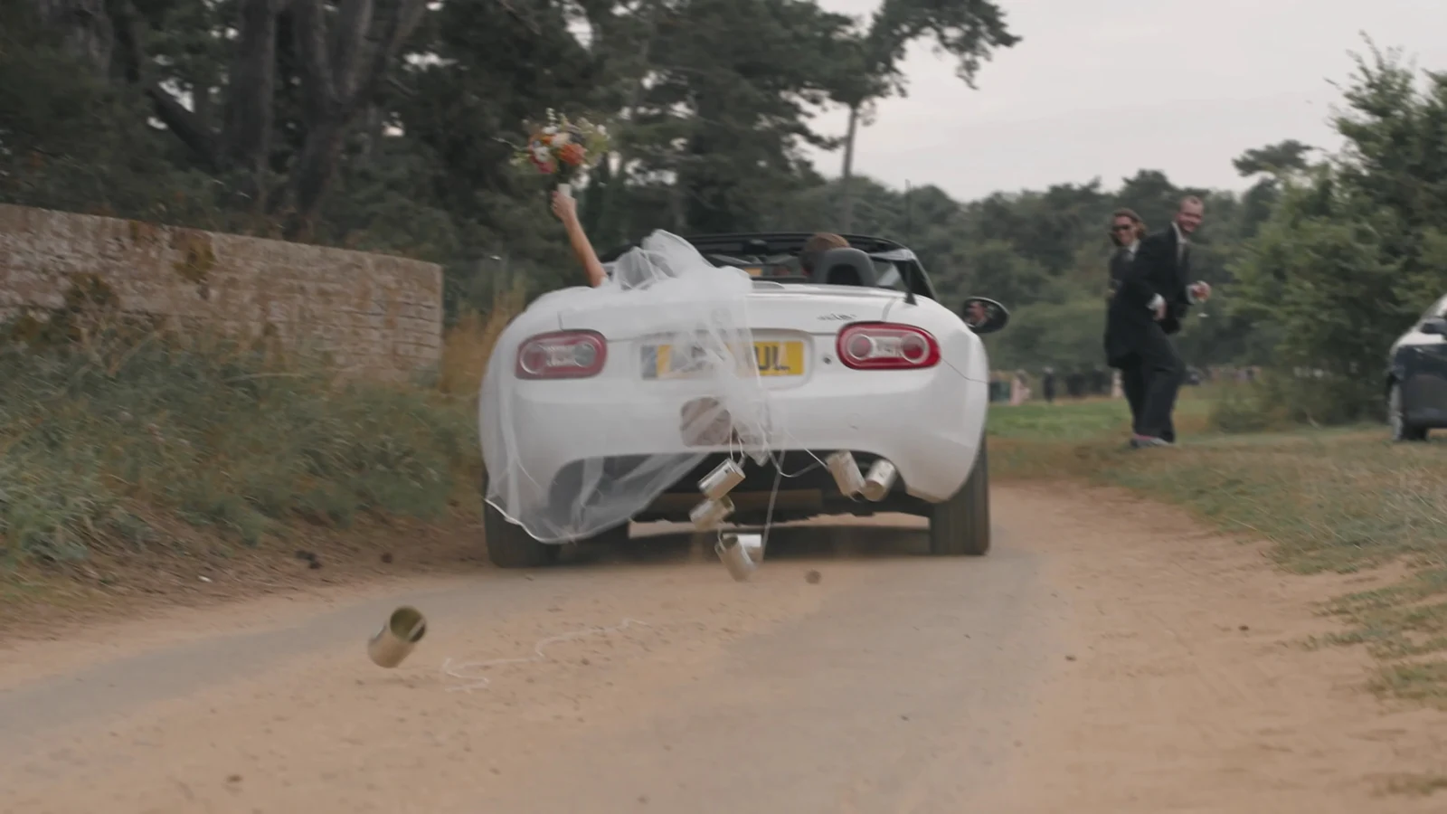 Film still: Harriet and Luke leaving in a white convertible