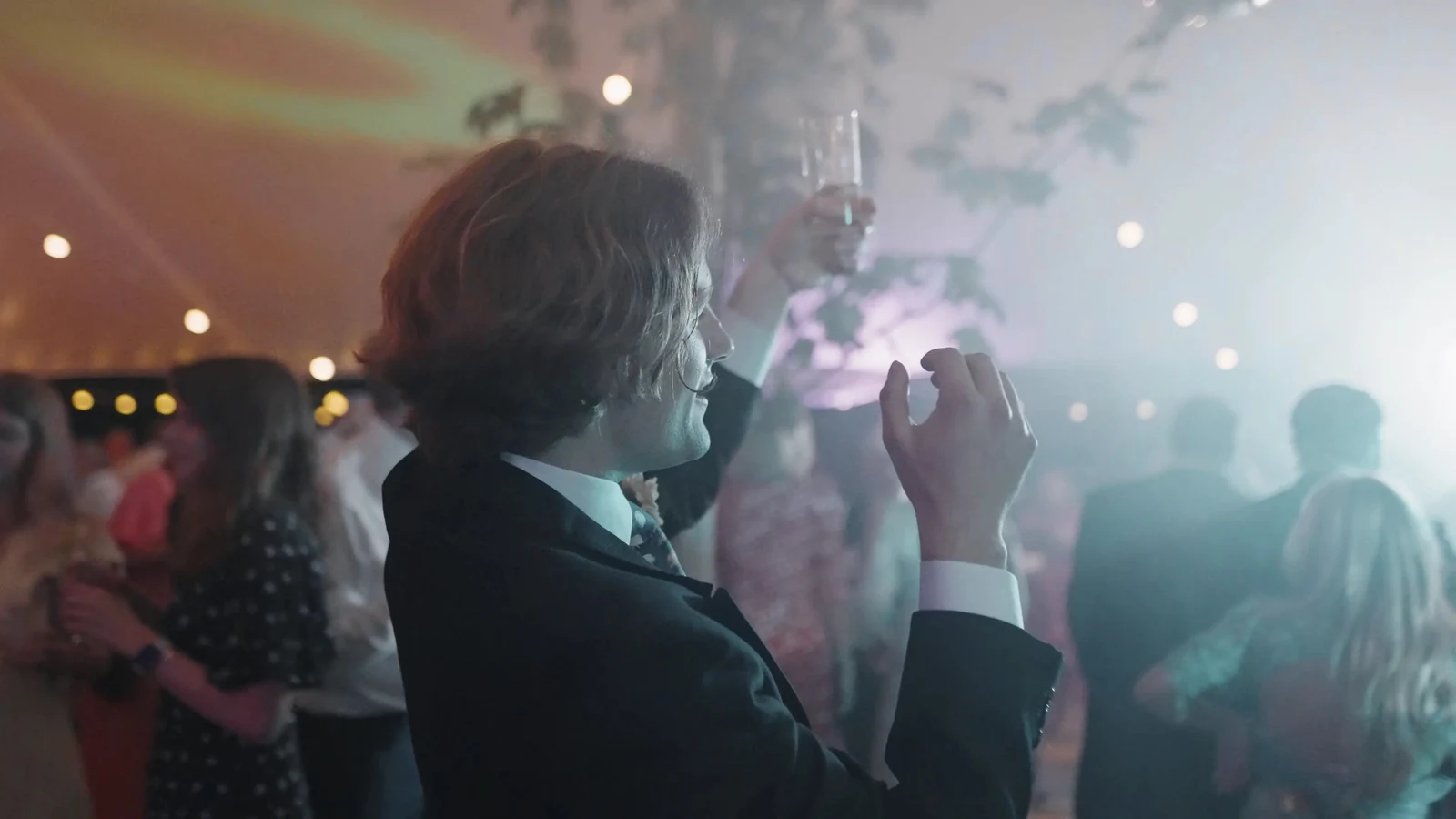 Film still: A guest singing into a microphone during the evening celebrations