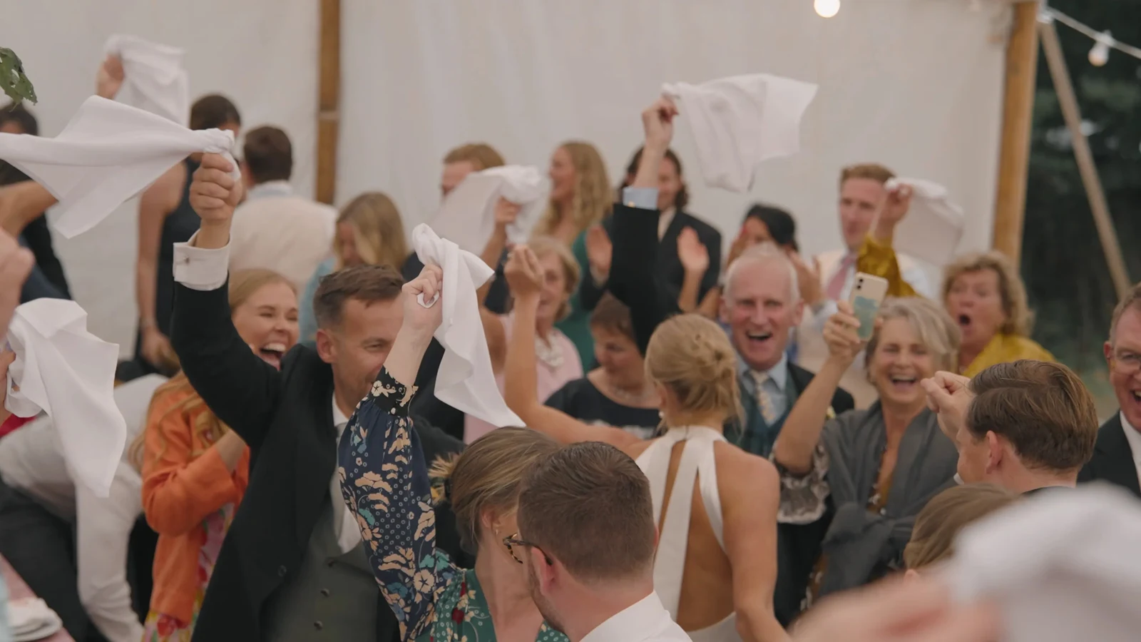 Film still: Guests waving napkins during the reception