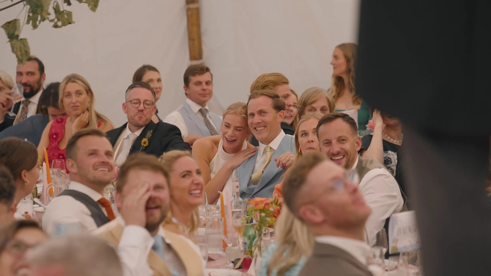 Film still: Wedding guests laughing during the speeches