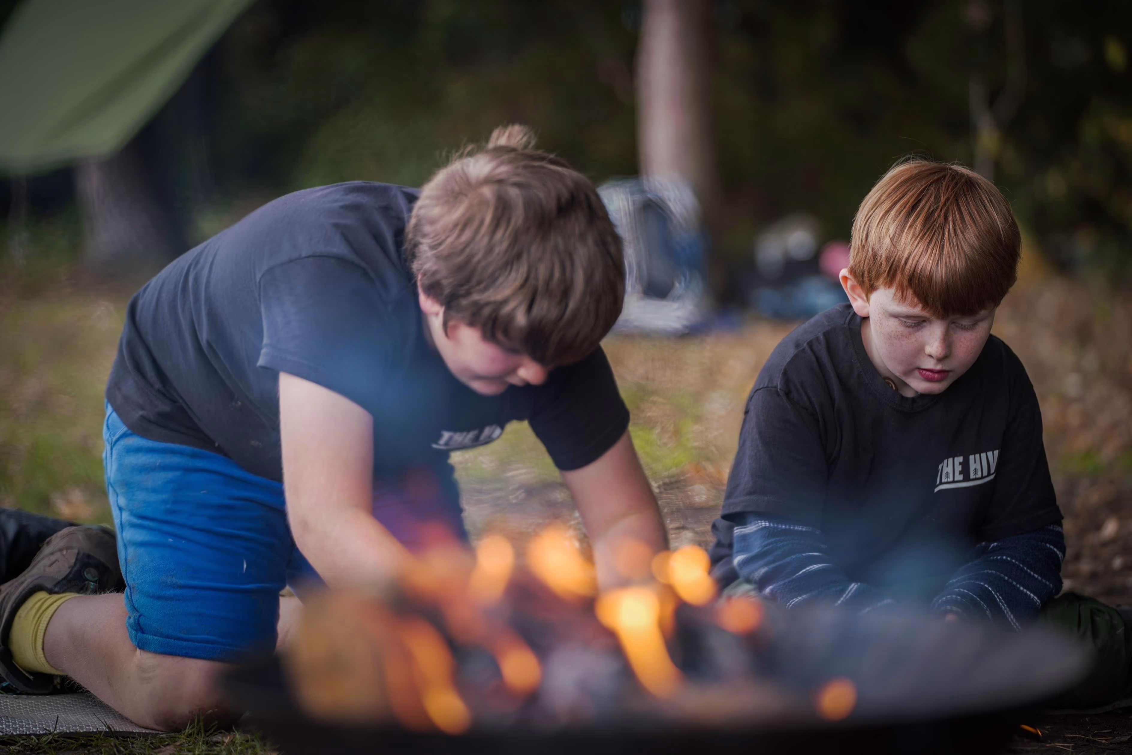 Instructor and child beside a fire during a camp activity