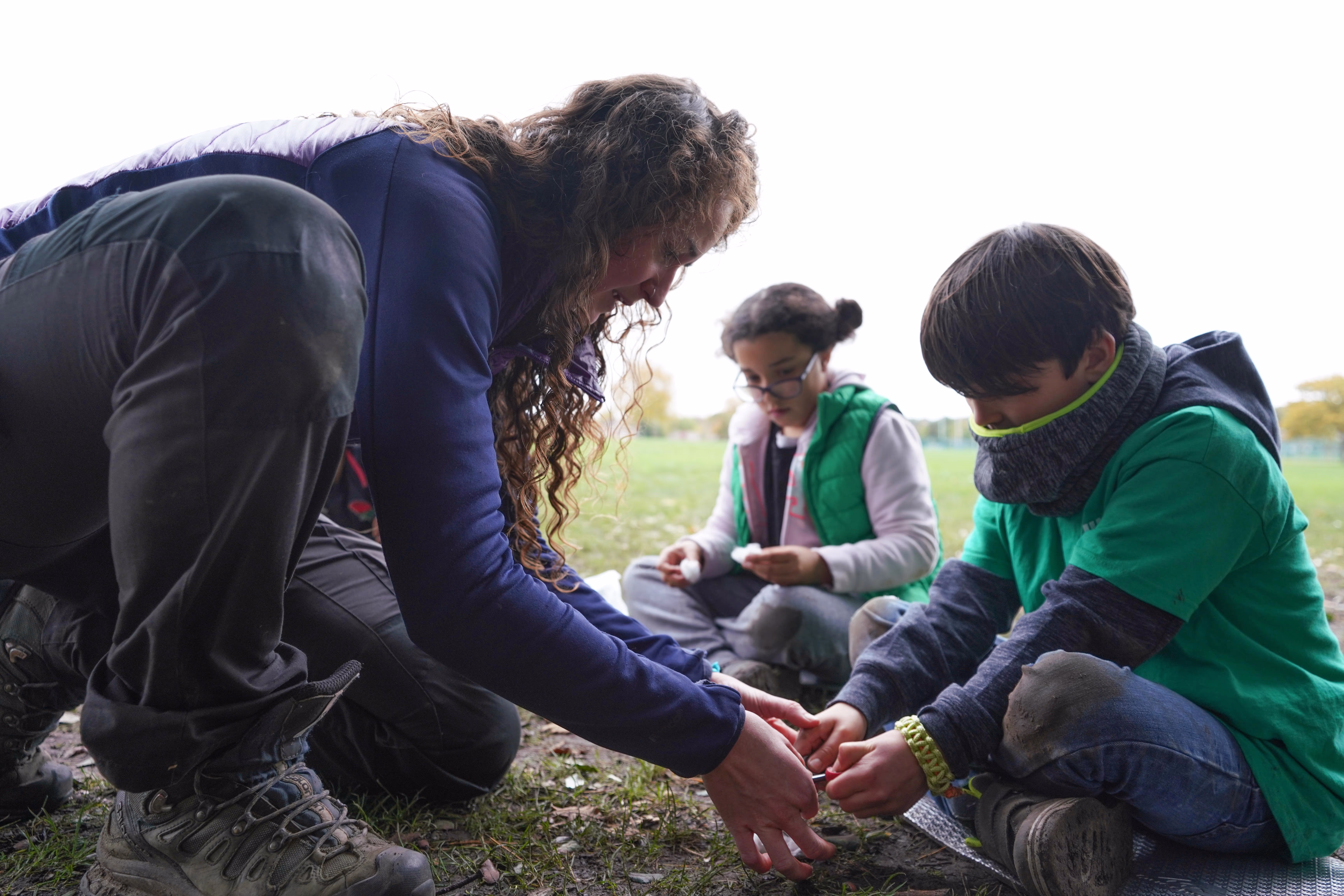 Instructor helping children with an outdoor camp activity