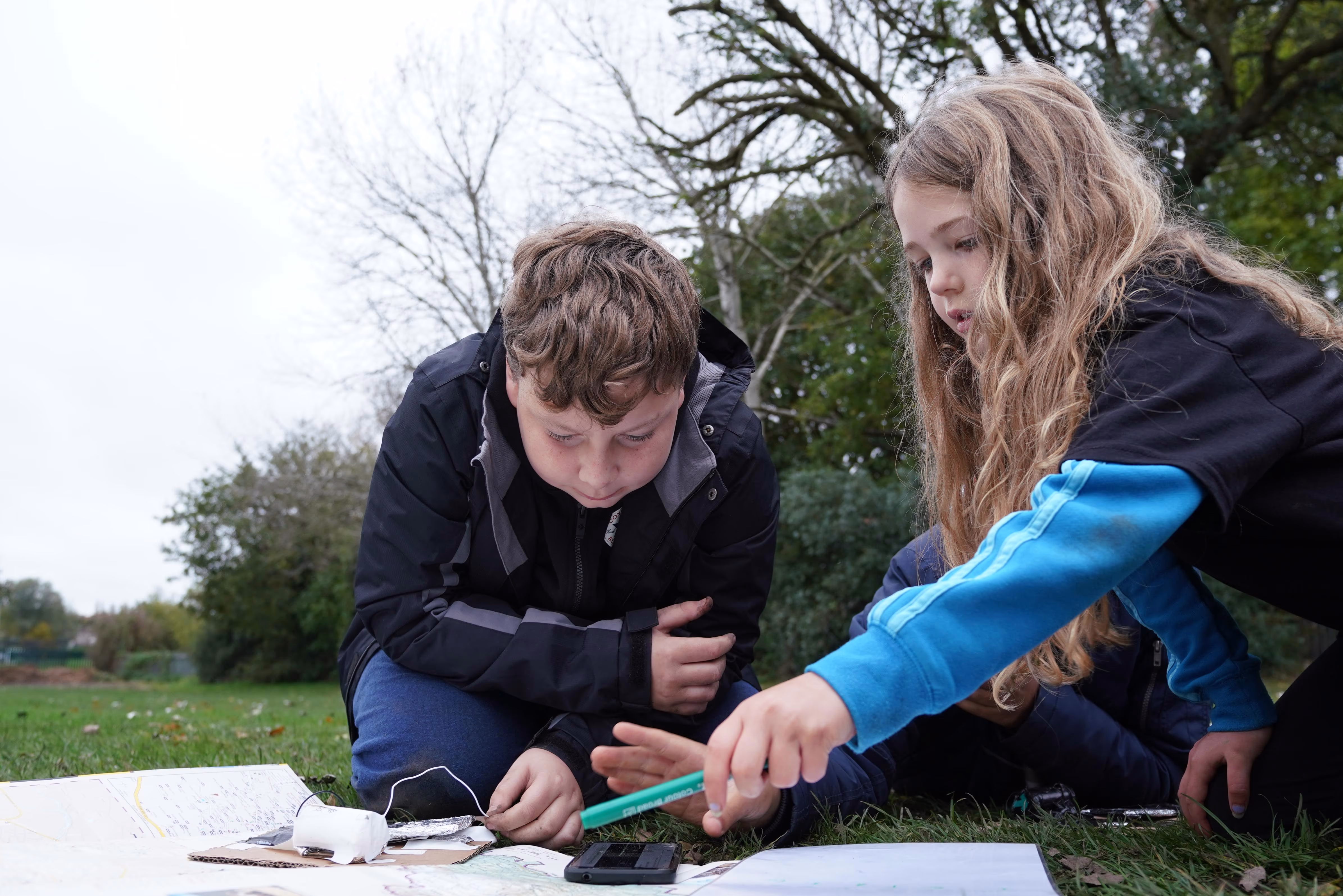 Children and an instructor studying materials on the grass