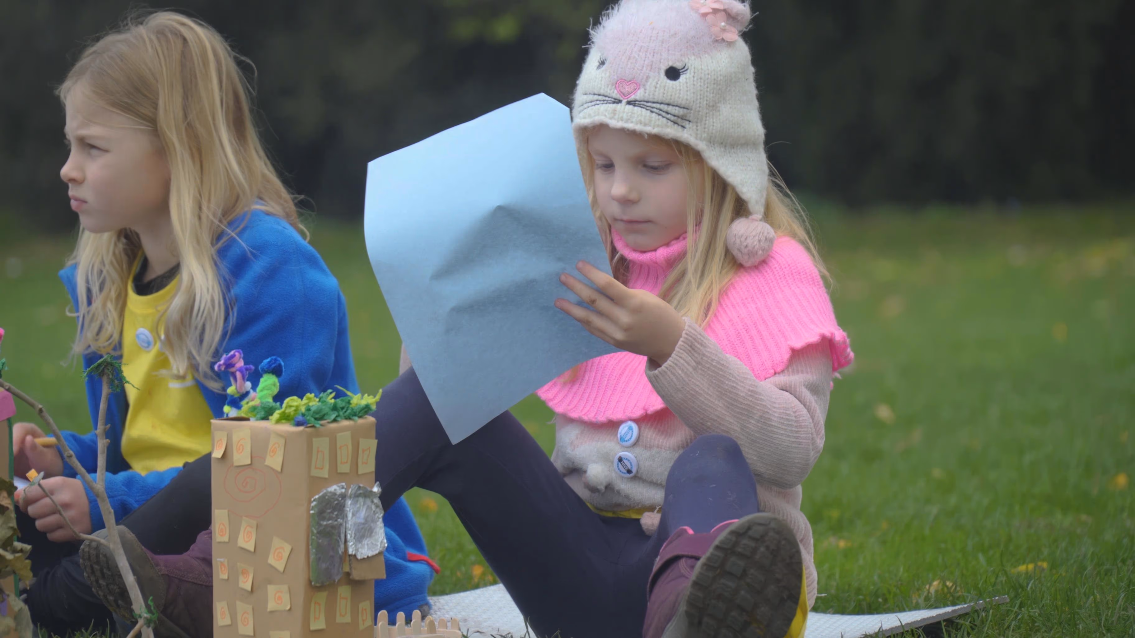 Children with a handmade model and paper during an outdoor workshop