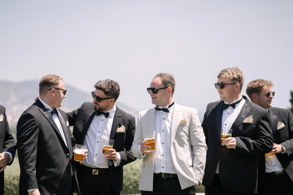 Wedding guests in suits chatting in the sunshine