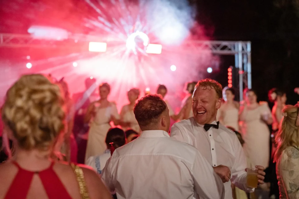 Guests celebrating on the dance floor under pink lights