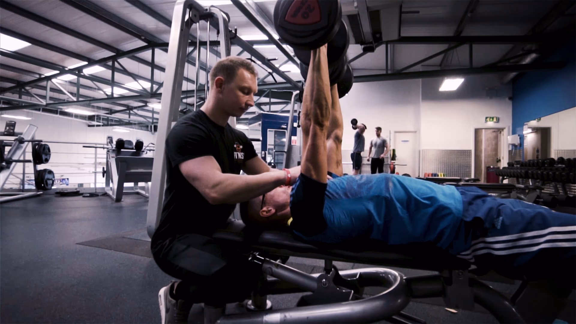 Personal trainer assisting a client with a leg raise exercise