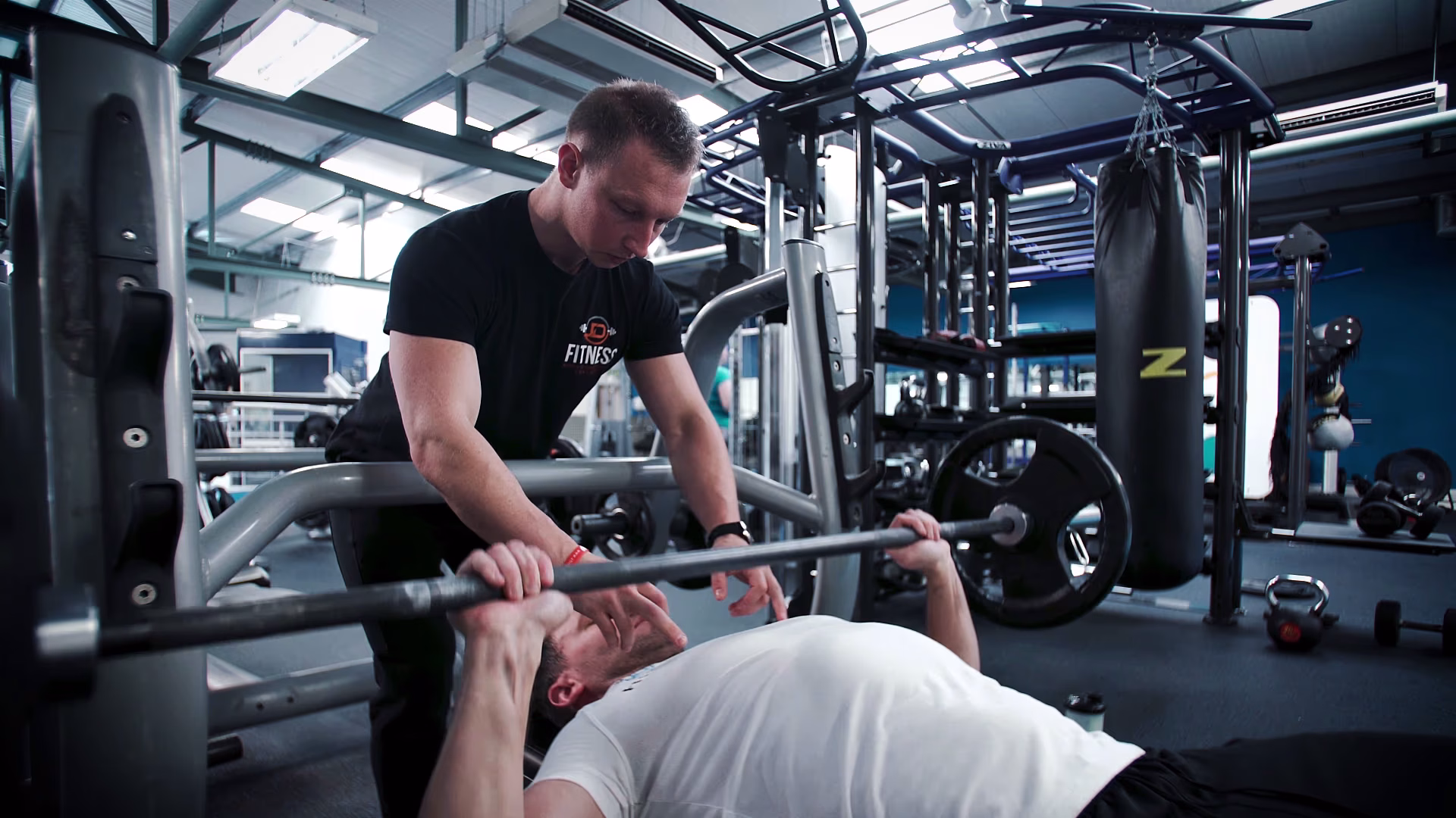 Trainer spotting a bench press during the Male Hypertrophy Camp