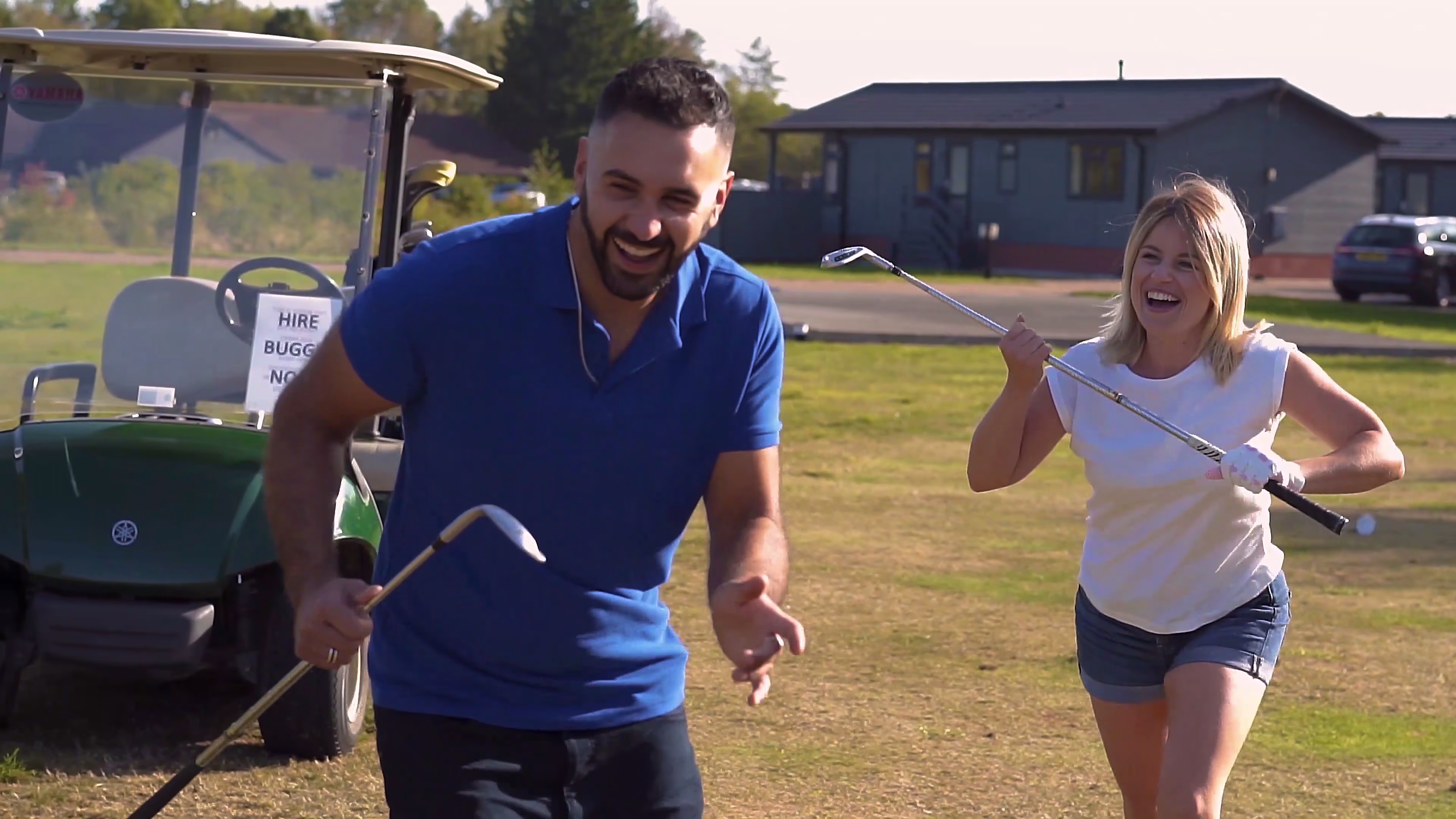 Jake and Lisa laughing beside a golf cart