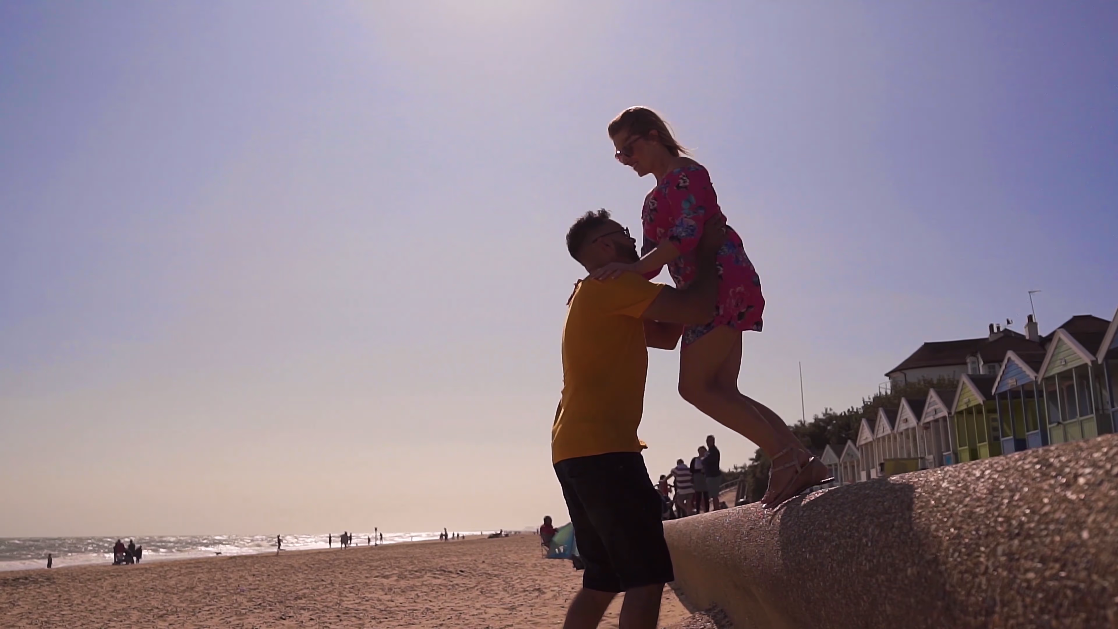 Jake lifting Lisa during their playful seaside date