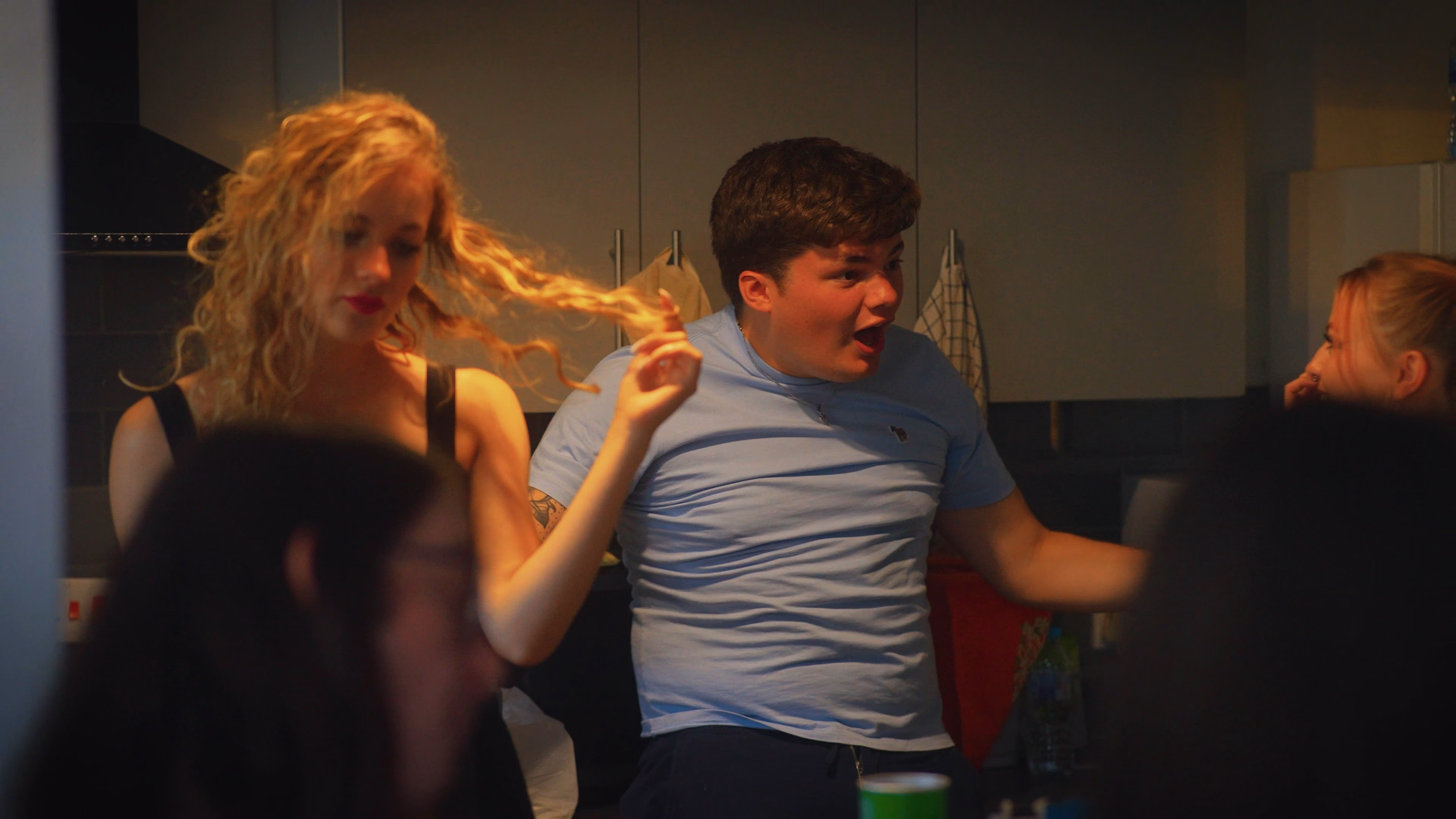 Guests gathering in the kitchen at the Mystery Man flat party