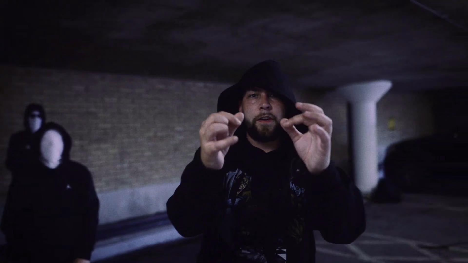New Guardz performer framed by anonymous masked figures in the Swarmer music video