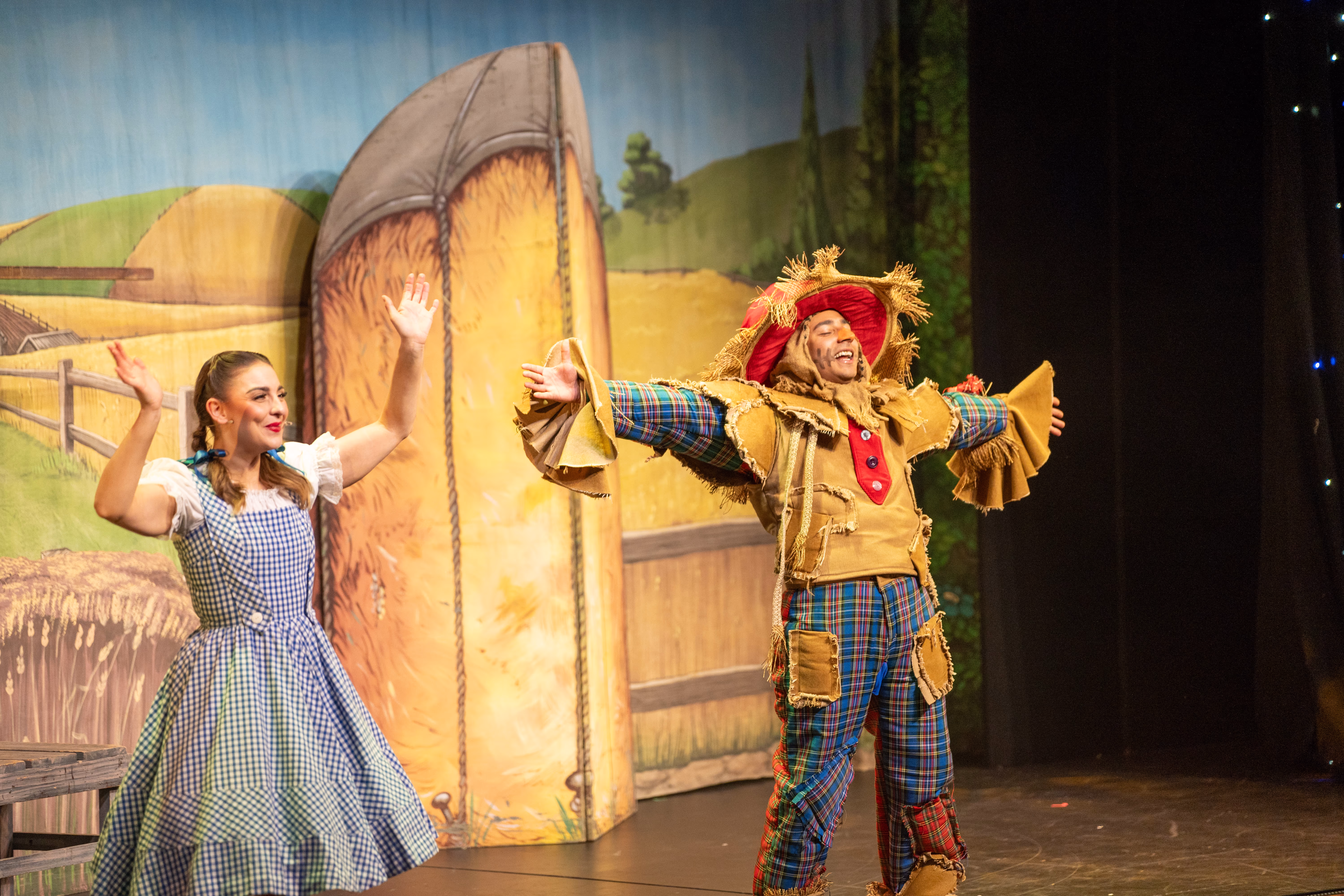 The Scarecrow performing beside Dorothy on the yellow brick road set