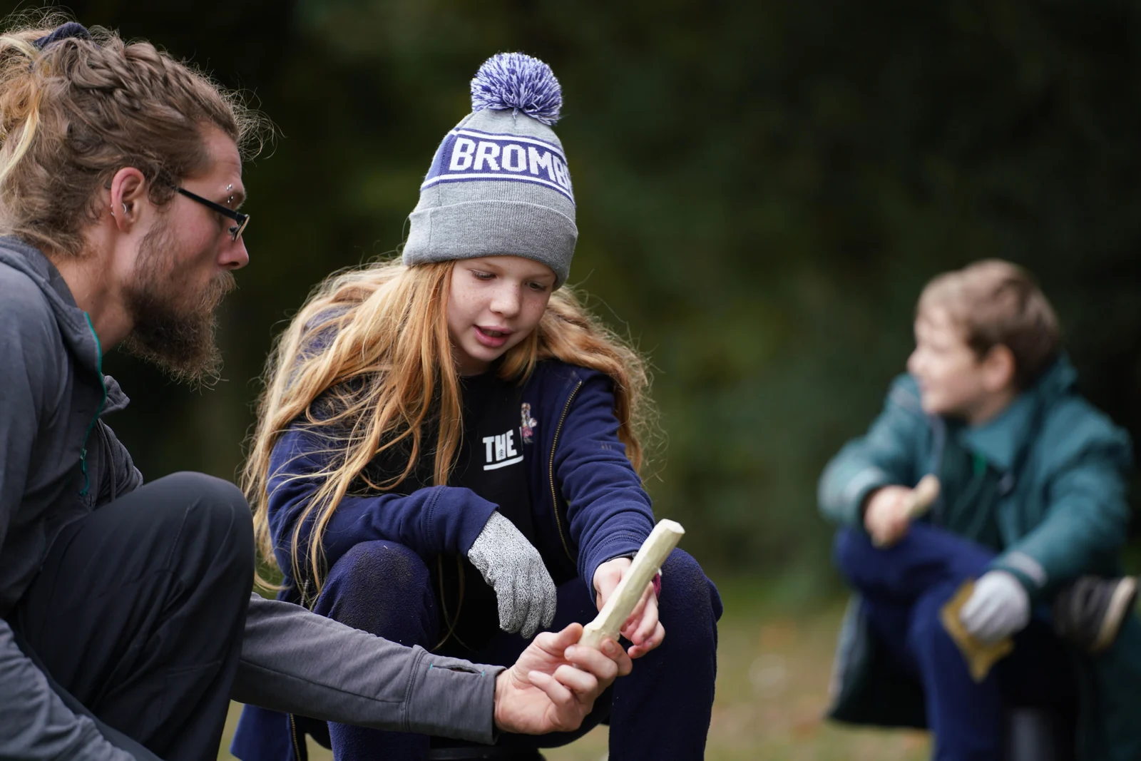 Instructor guiding a child through an outdoor bushcraft task at The Hive