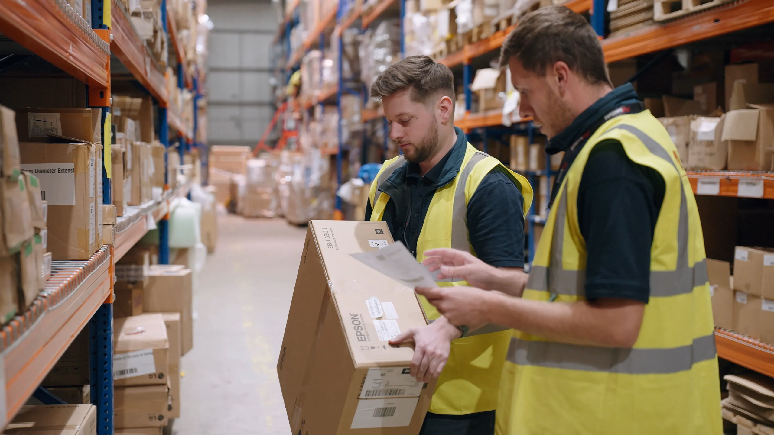 Two logistics team members checking a box in the warehouse