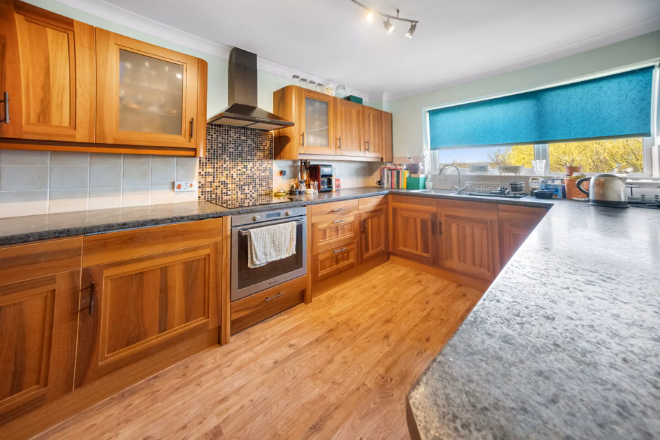 Kitchen with timber cabinets and a turquoise window blind — 13 Furness Close