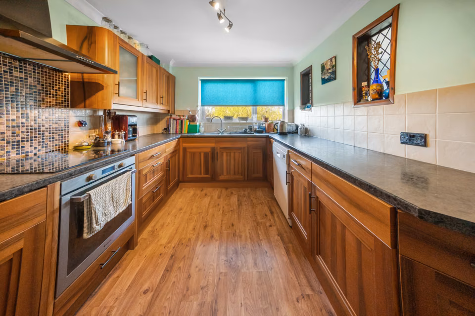 Galley kitchen with timber flooring and built-in oven — 13 Furness Close