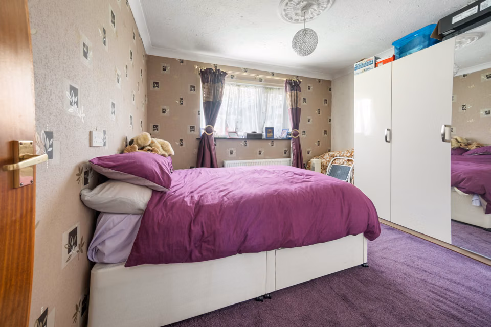 Bedroom with a purple bedspread and fitted cupboards — 13 Furness Close
