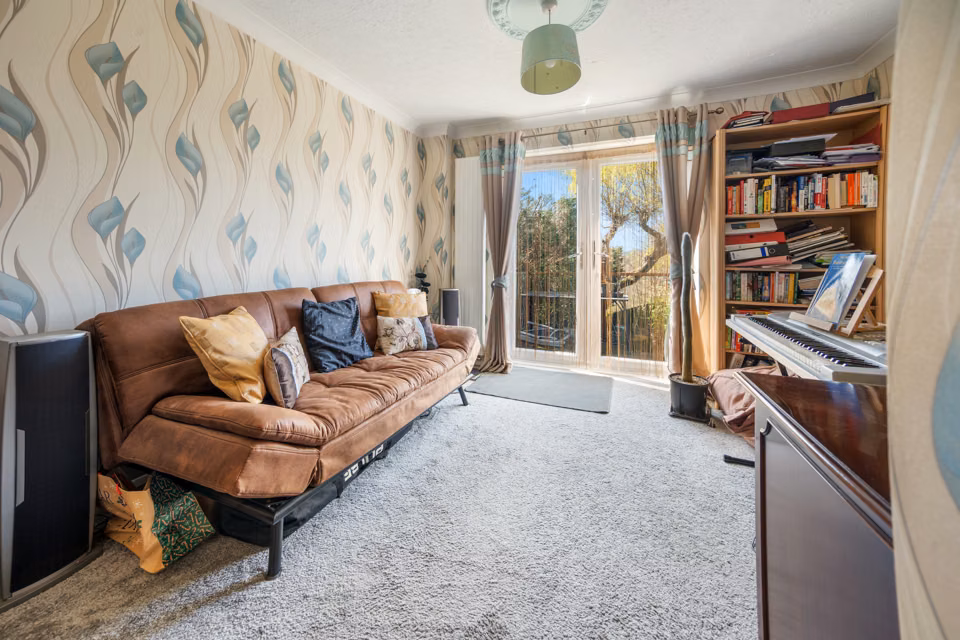 Sitting room with a sofa and doors towards the garden — 13 Furness Close