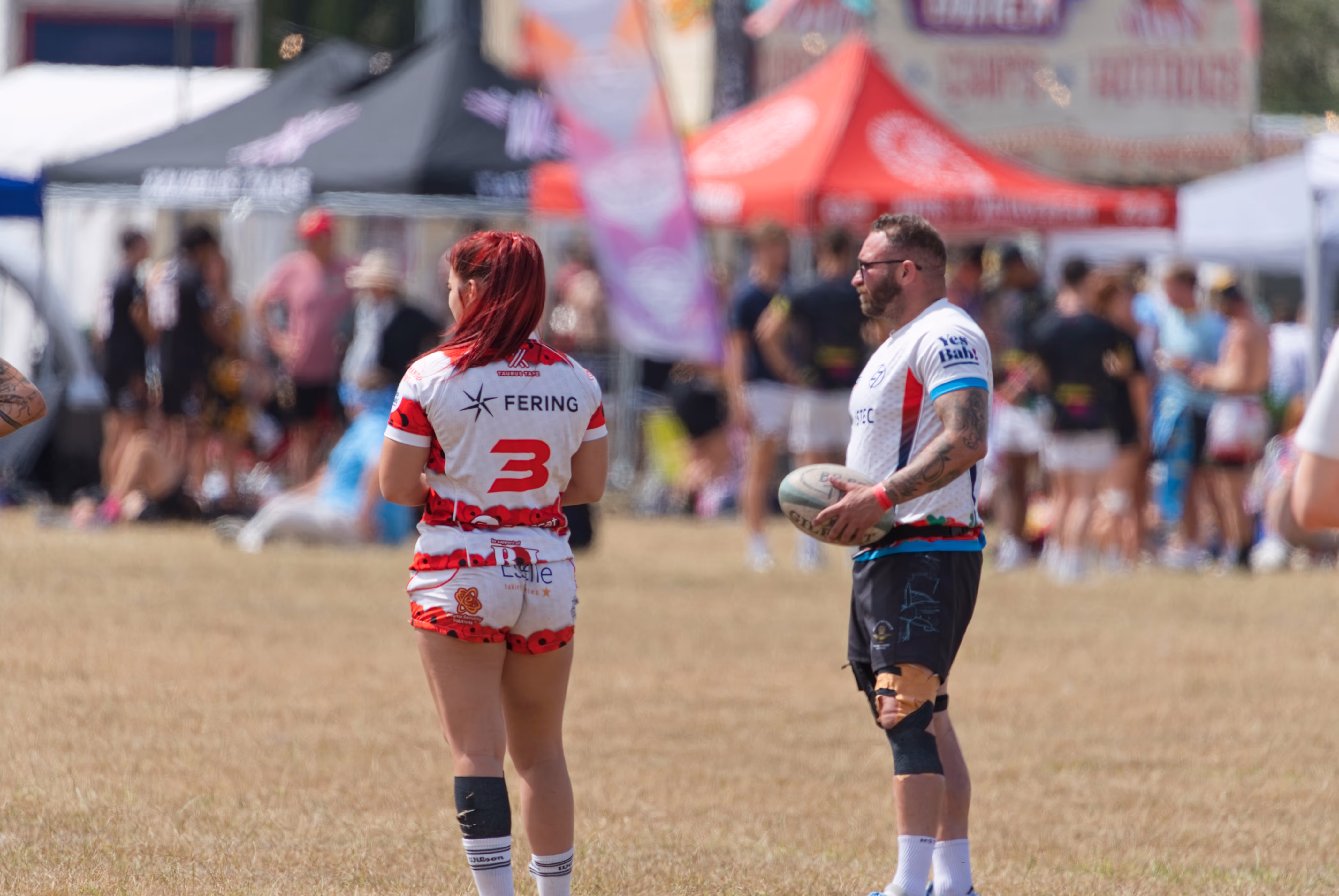 Rugby match action with spectators and event tents at Cheltenham Racecourse