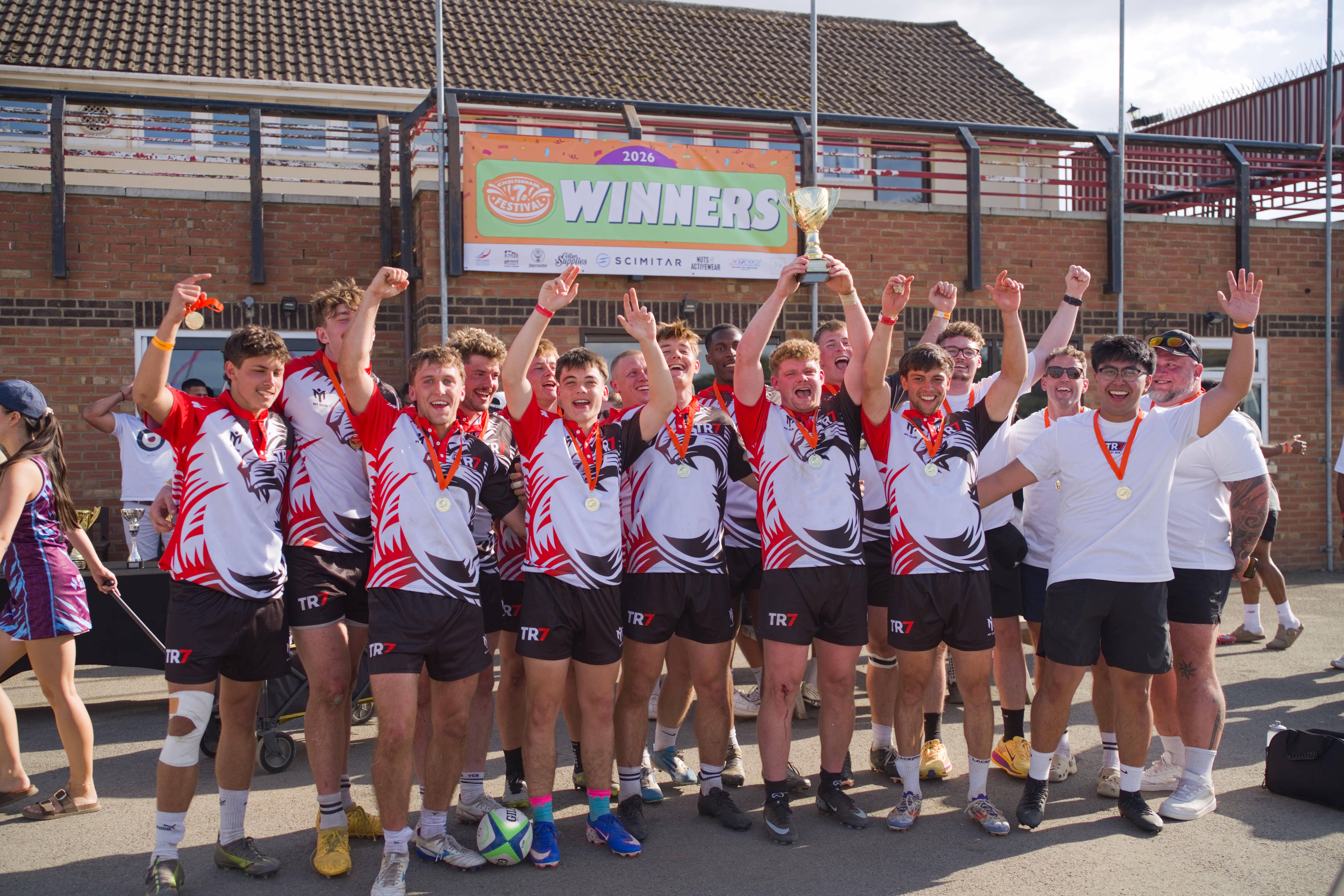 TR7 squad celebrating with the winners banner and trophy at Cheltenham
