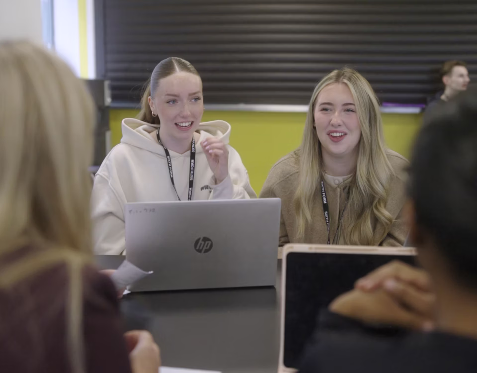 KES Sixth Form students collaborating around a laptop in class
